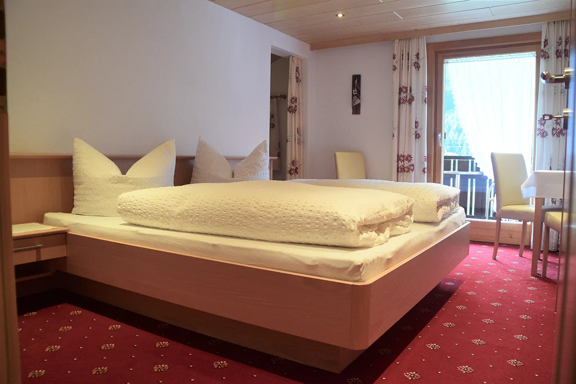 Schlafbereich der Ferienwohnung mit Doppelbett, Balkontür und Tür zum Bad